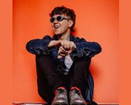 boy sitting in front of orange background
