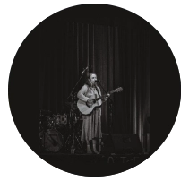 girl holding guitar and singing into microphone
