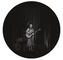 girl holding guitar and singing into microphone